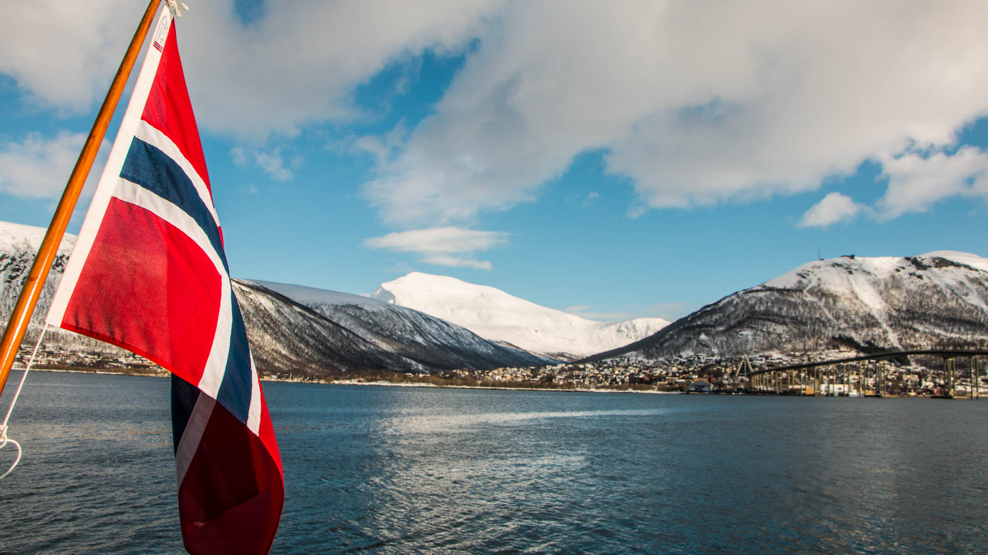 Skitour-Anreise per Boot auf dem Lyngenfjord mit schneebedeckten Bergen und Tromsø im Hintergrund.