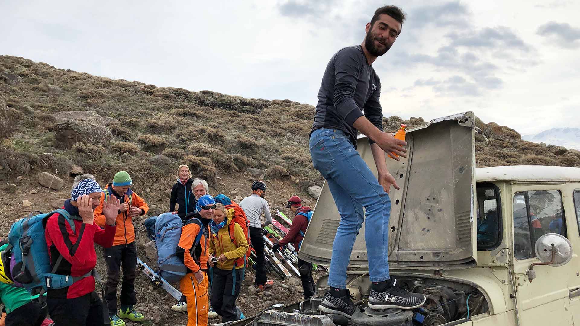 Skitourengeher entladen Ski und Ausrüstung von einem Geländefahrzeug an einem Berghang im Iran.