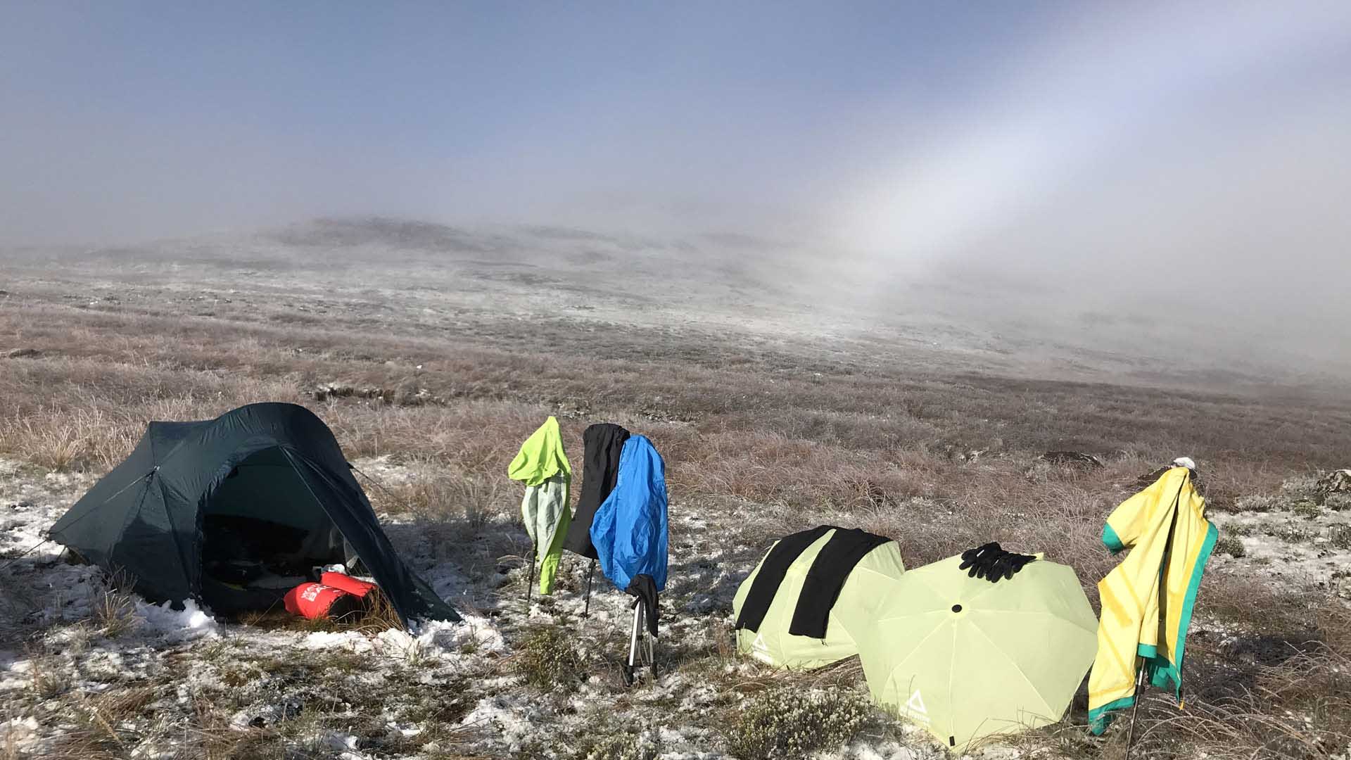 Trekking in den Drakensbergen Südafrika: Biwakplatz mit zwei Kuppelzelten und zum Trocknen gehängter Kleidung