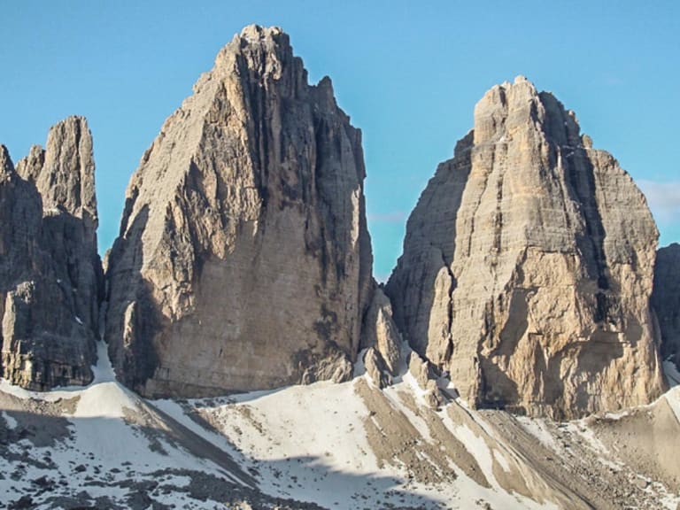 Bergwanderung zu den Drei Zinnen: Frontalansicht der drei Felstürme aus Dolomitgestein über einem felsigen Hochplateau