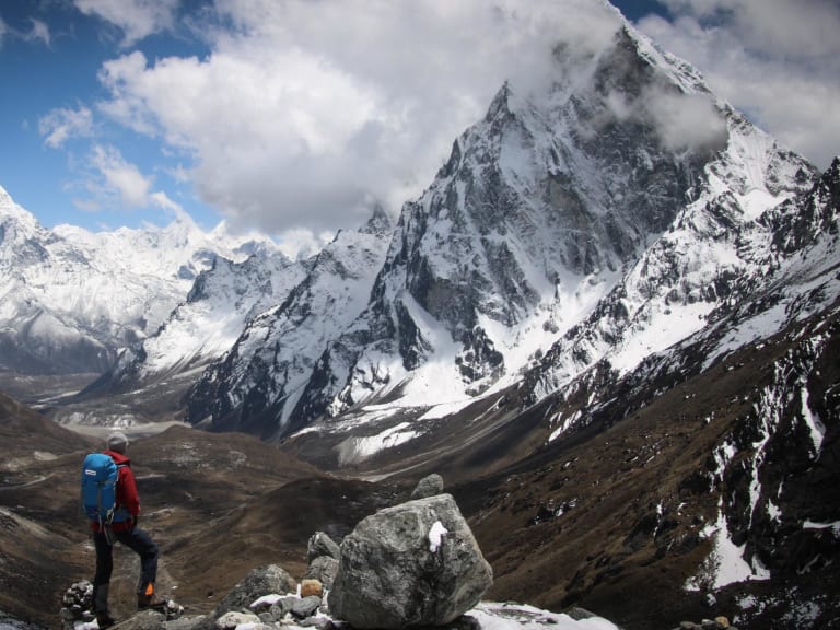 Höhenbergsteiger steht auf felsigem Aussichtspunkt und blickt auf den Cholatse im Gokyotal, Khumbu.