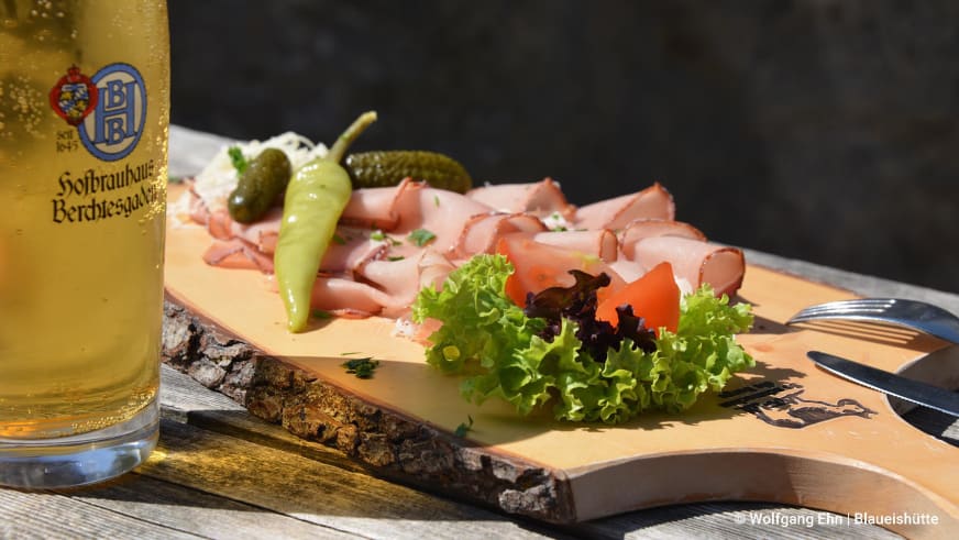 Bergwanderung in Berchtesgaden: rustikale Brotzeit-Platte mit Aufschnitt und Hofbräuhaus-Bier an der Blaueishütte.