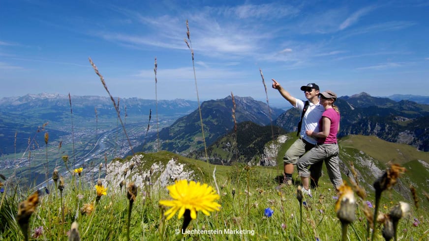 Bergwanderung am Rabbenstein: zwei Wanderer auf grasigem Bergrücken mit Blick ins besiedeltes Tal.