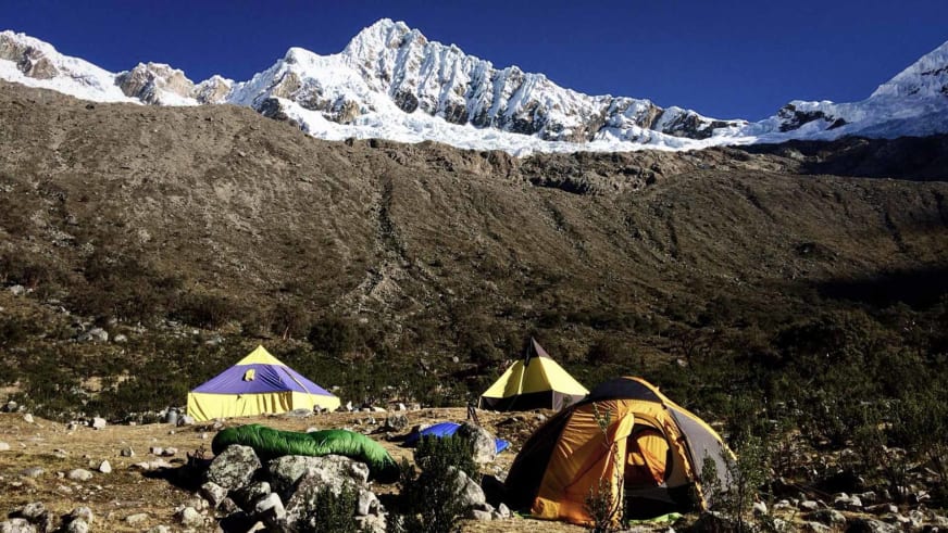 Expedition Alpamayo: Basislager mit Kuppel- und Rundzelt auf steinigem Plateau vor vergletschertem Gebirgskamm.
