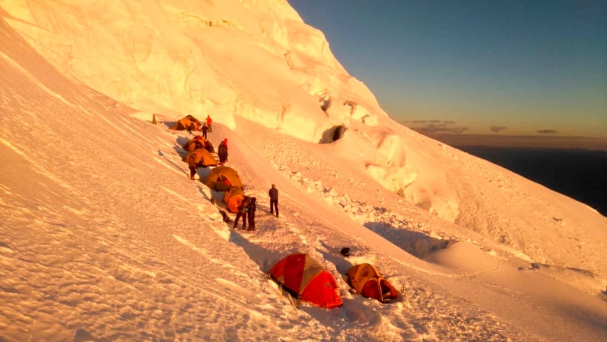 Expedition Huascarán: Hochlager 2 mit Zeltreihe auf Schnee-Terrassen neben Gletschereiswand, sechs Höhenbergsteiger sichtbar.