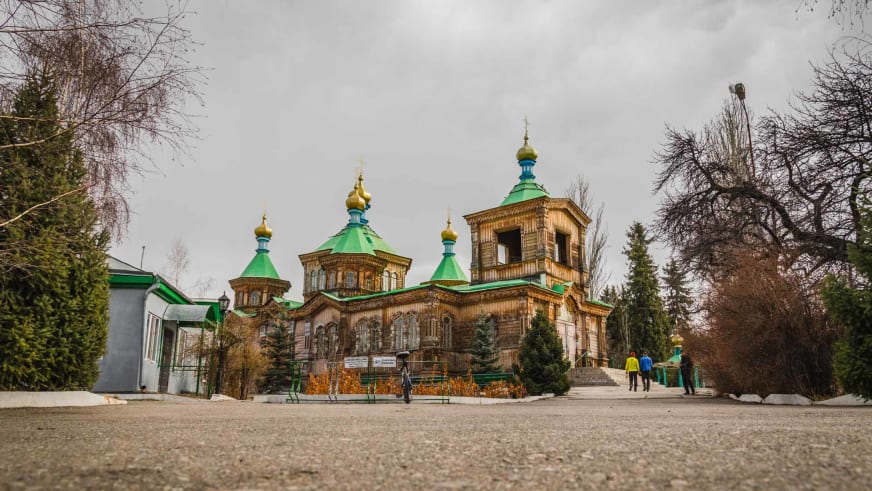 Skitour-Reise in Karakol: hölzerne orthodoxe Kirche mit grünen Kuppeln und goldenen Zwiebeltürmen in Kirgistan.