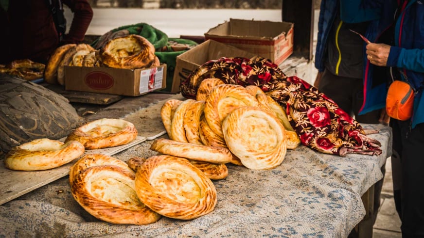 Skitour in Kirgistan: Skitourengeher betrachten Fladenbrot-Spezialitäten an einem Marktstand in Karakol.