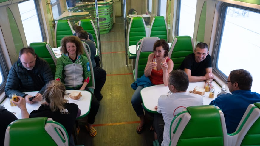 Reisegruppe beim Mittagessen in einem Abteil der Transsibirischen Eisenbahn auf dem Weg zur Skitour in Sibirien.