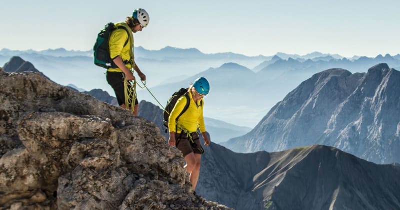 Bergtour am Jubigrat der Zugspitze: zwei Bergsteiger klettern gesichert mit Seil über Kalkfels.