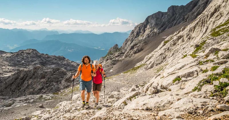 Bergtour im Steinernen Meer: zwei Wanderer auf felsigem Karstpfad im Nationalpark Berchtesgaden mit weitem Bergpanorama.