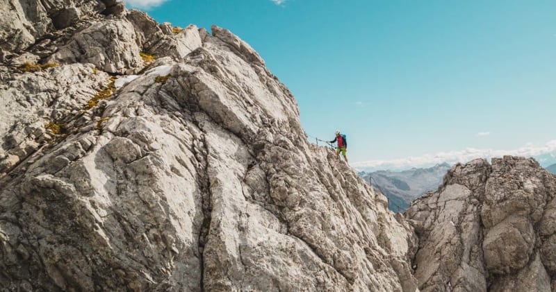 Watzmann-Ueberschreitung: ein Bergsteiger quert einen schmalen Felsgrat zwischen zwei Kalktuermen im Hochgebirge.