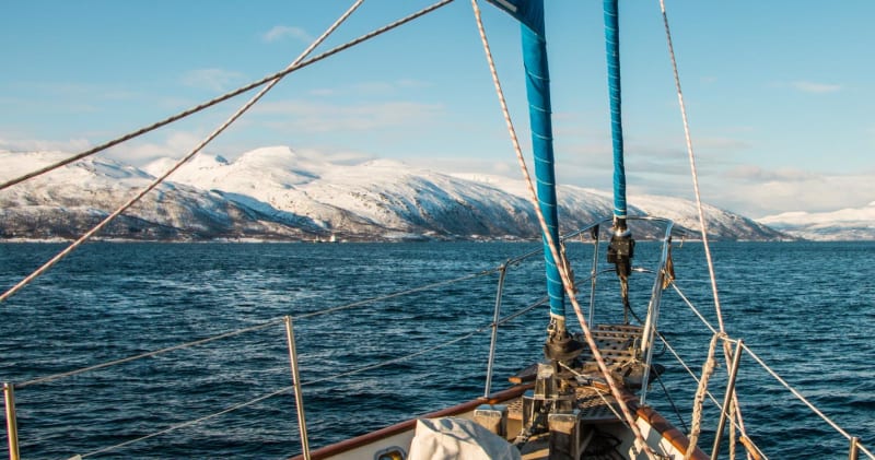 Skitour vom Schiff: Blick vom Bugdeck über einen Fjord auf schneebedeckte Berghänge in Norwegen.