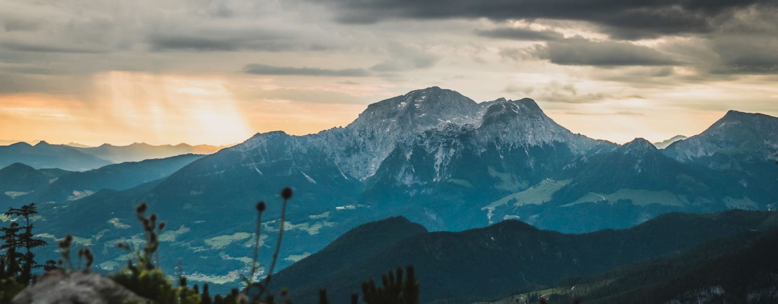 Bergwanderung in Berchtesgaden: Blick auf einen felsigen Kalksteingipfel mit bewaldeten Vorbergen im Abendlicht.