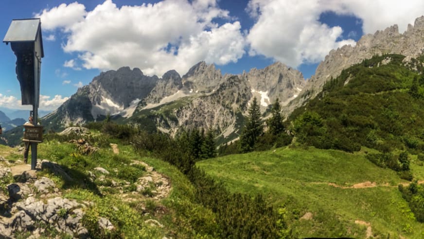 Bergwanderung am Wilden Kaiser: drei Bergwanderer mit Rucksack und Stöcken am Wegweiser Zwicke Stelle.