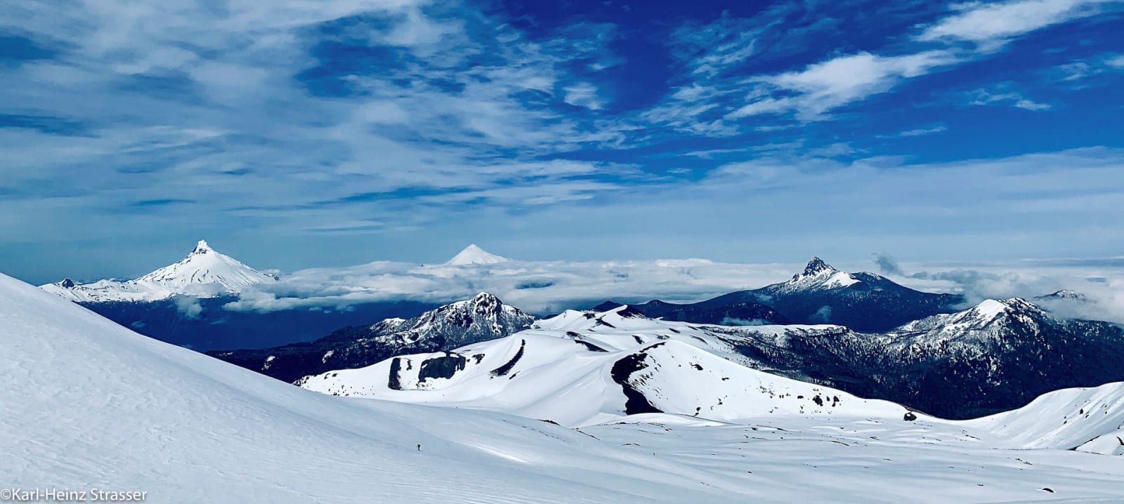 Bergtour am Vulkan Puntiagudo und Osorno: Bergsteiger traversiert winterlichen Schneehang im Panorama.