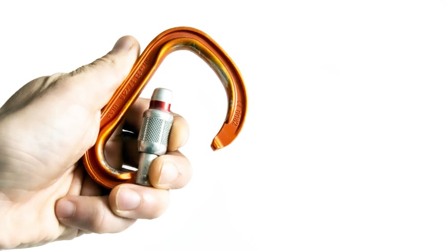 Klettern: Nahaufnahme eines geöffneten orangefarbenen Petzl Attache Schraubkarabiners mit CE-Kennzeichnung.