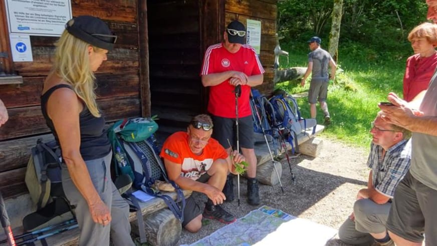 Bergwanderung an der Bedarfshaltestelle Kessel: Gruppe von sechs Wanderern studiert eine ausgebreitete Karte