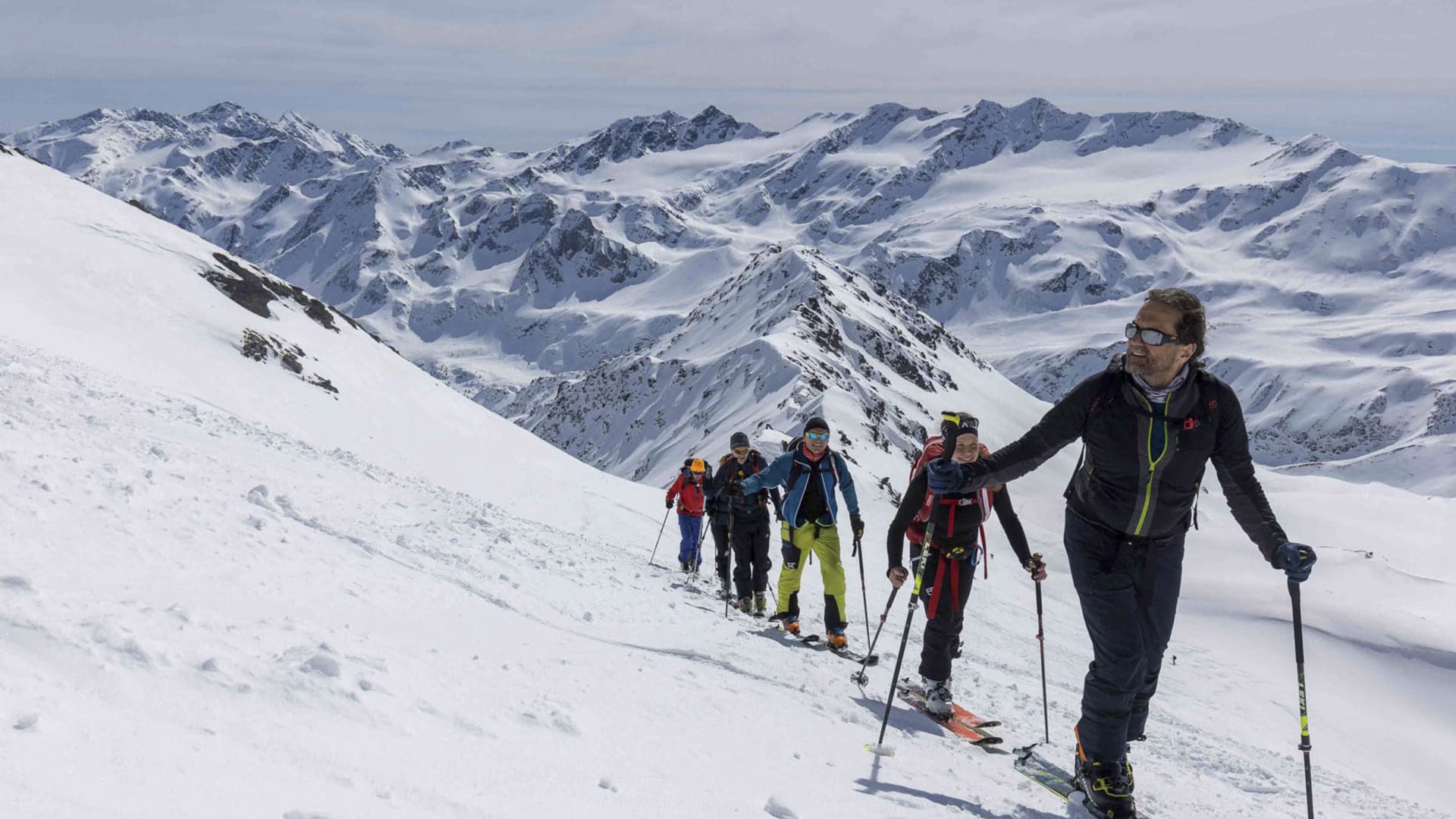 Fünf Skitourengeher steigen mit Fellen und Rucksäcken am verschneiten Hang zur Zufallspitze auf.