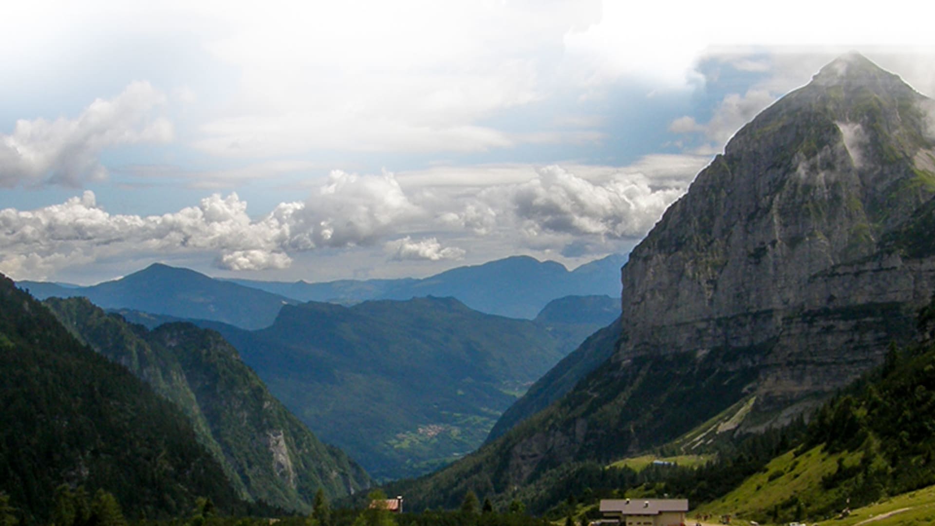 Blick auf Schutzhütte am Lago Nembia mit steilem Kalkgipfel und Talblick nahe Molveno in der Brenta-Gruppe.