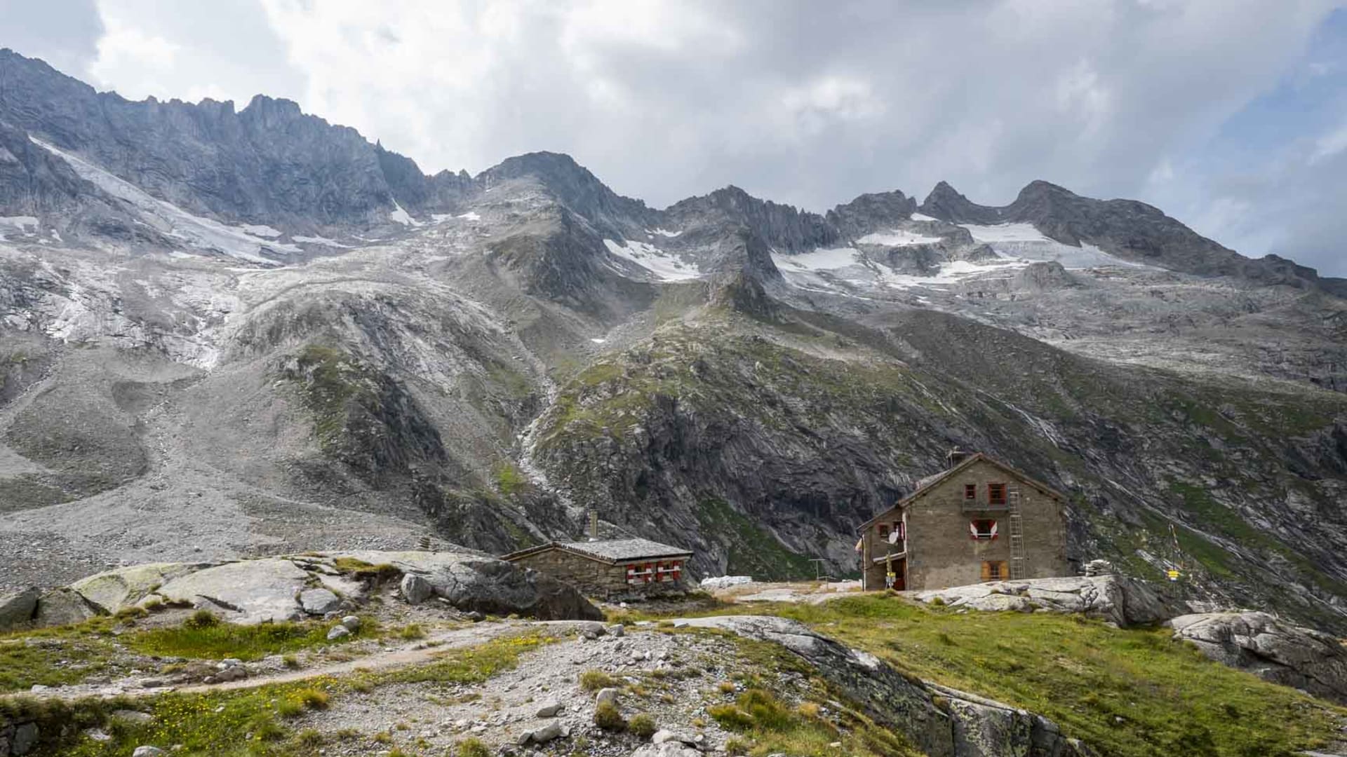 Bergwanderung zur Richter Hütte im Zillertal: zwei Steingebäude auf felsiger Geländestufe vor zackigem Gebirgsmassiv