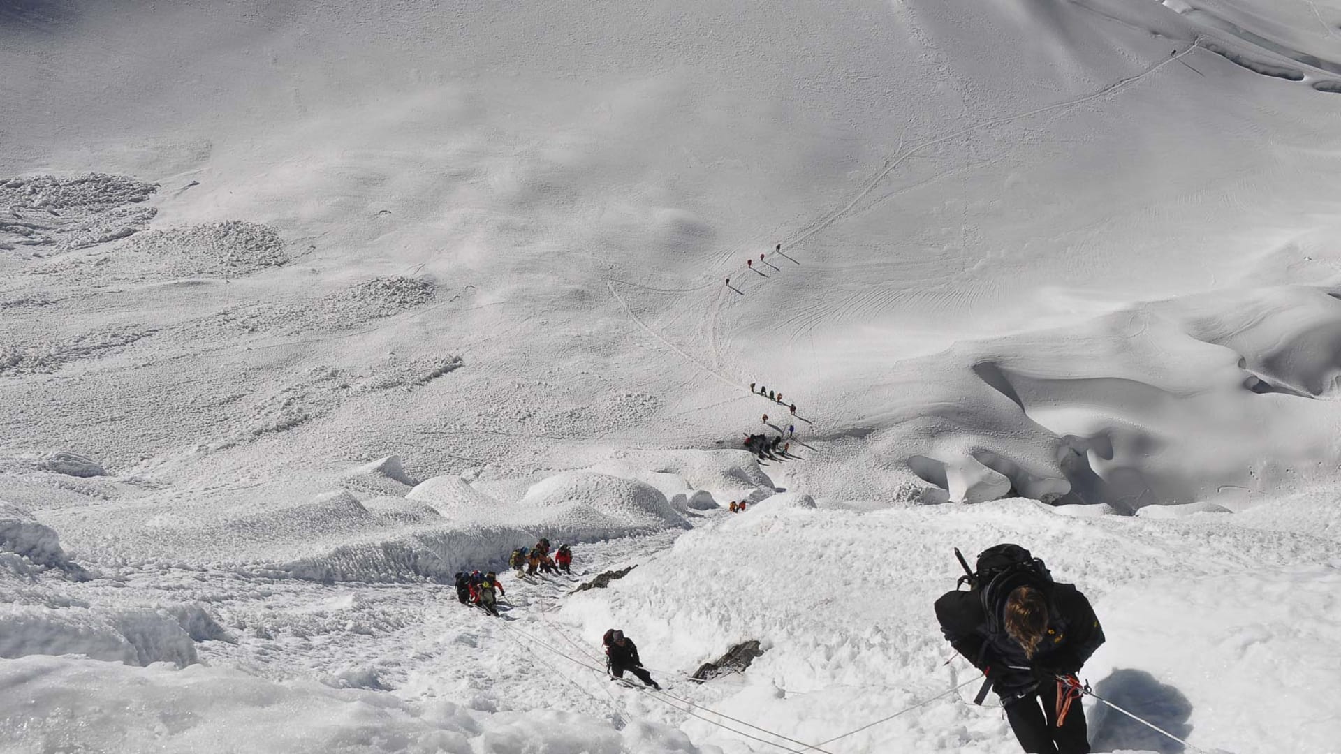 Expedition am Island Peak: Höhenbergsteiger sichern sich am Fixseil durch einen zerklüfteten Gletscherbruch mit Seracs und Spalten.