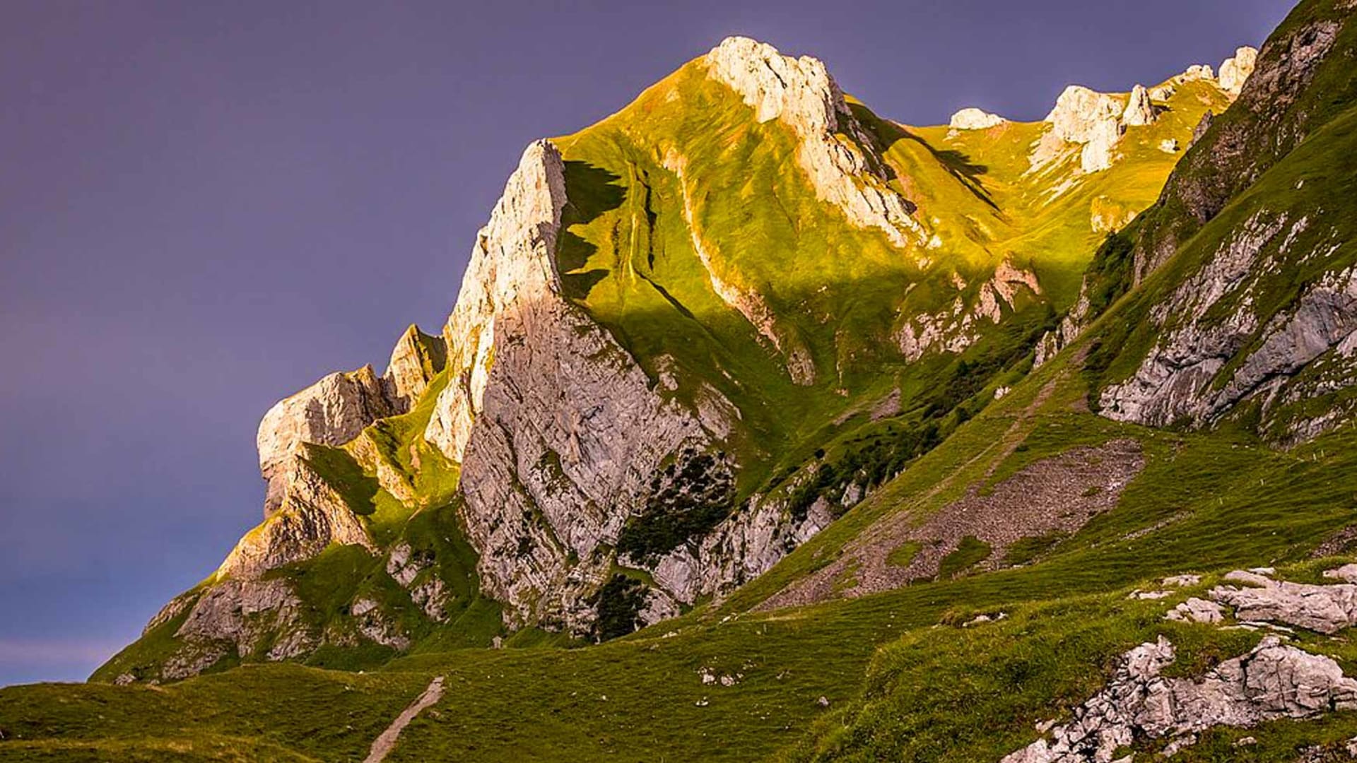 Bergwanderung zur Meglisalp im Alpstein: Wanderpfad auf Wiesenhang vor Kalksteinmassiv mit Felsgipfeln.