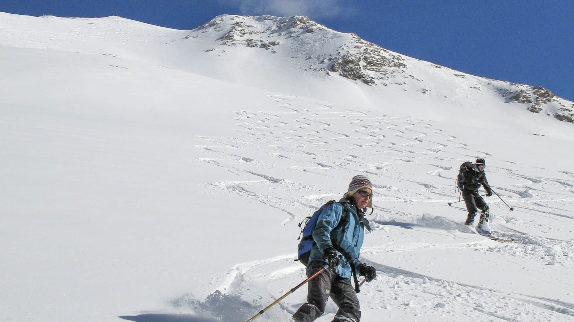 Zwei Skitourengeher fahren einen schneebedeckten Hang im Taurusgebirge mit Pulverschnee ab.