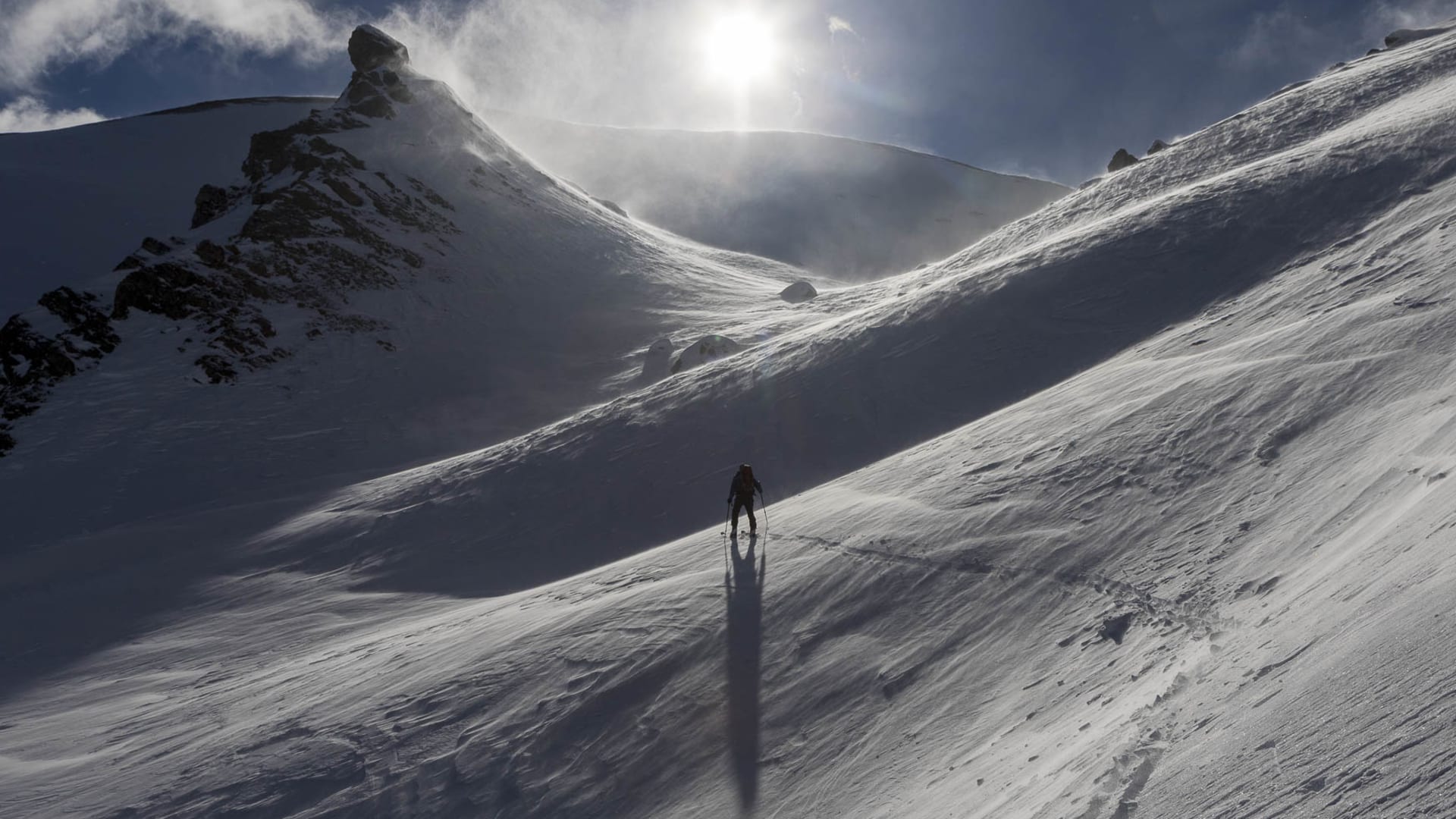 Einzelner Skitourengeher steigt im Gegenlicht den Schneehang zum Geier bei der Lizumer Hütte auf.