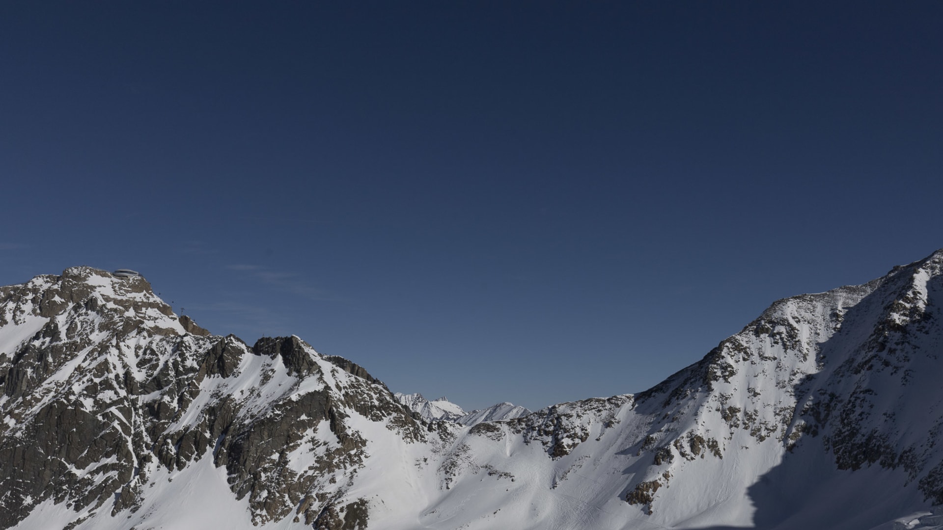 Skitour am Mittelbergjoch in den Ötztaler Alpen: unberührtes Schneeplateau zwischen felsigen Gipfeln unter tiefblauem Himmel.