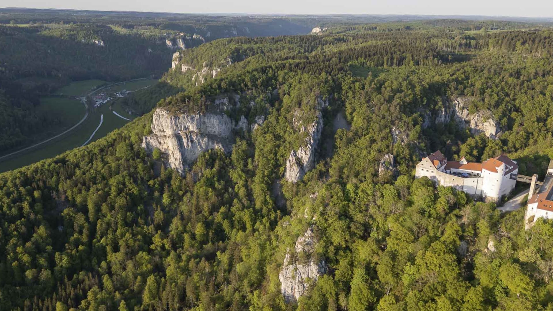 Luftaufnahme Donautal: Klettern an freistehenden Kalksteinfelsen der Schwäbischen Alb mit Burganlage auf Felsplateau