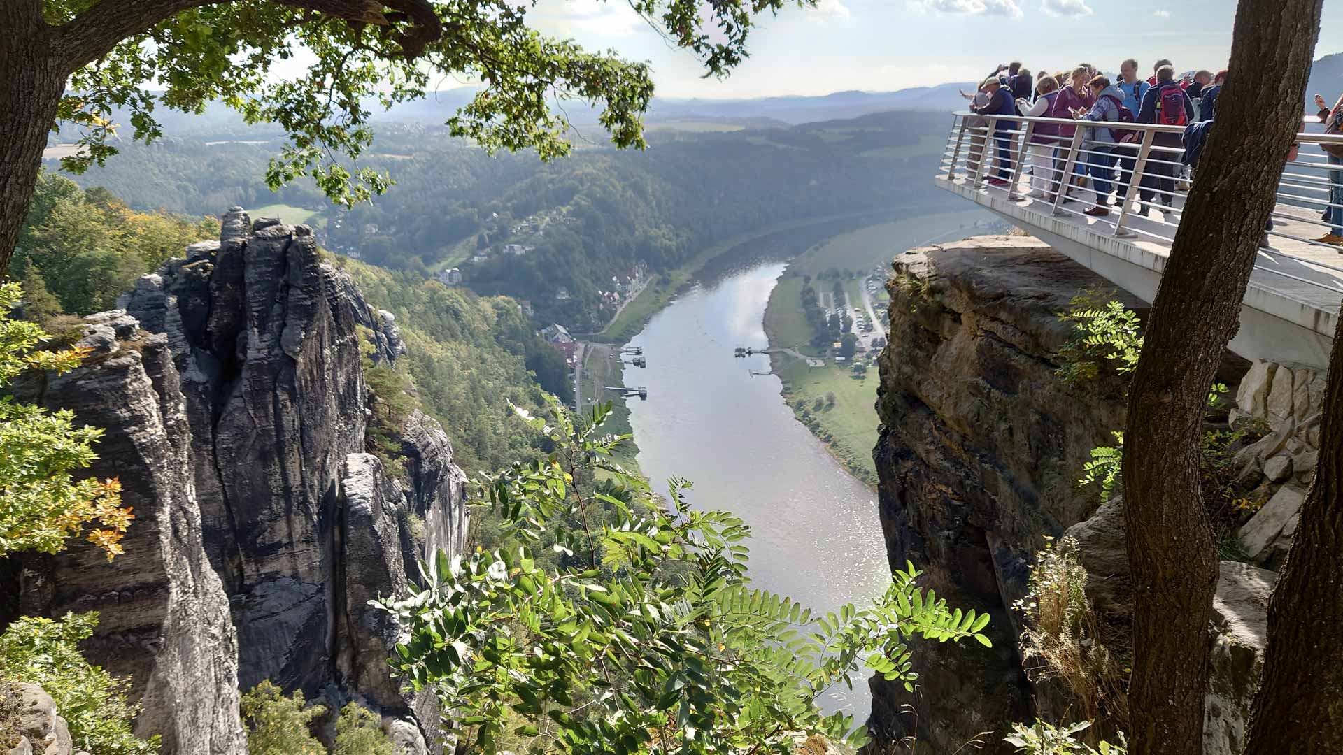 Bergwanderergruppe auf der Aussichtsplattform Bastei mit Blick auf den Fluss und das bewaldete Elbtal.