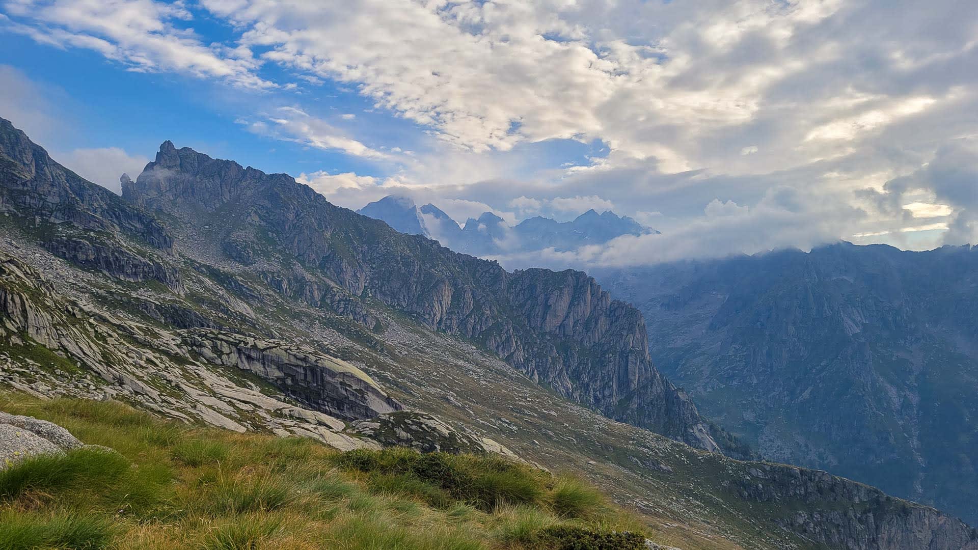 Bergwanderung im Bergell mit Blick auf gezackten Felsgrat und Gebirgszüge im Hintergrund.