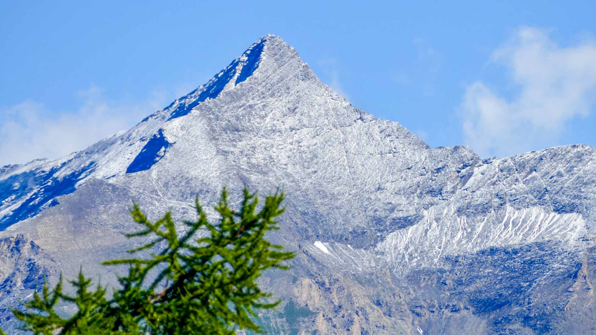 Bergwanderung am Rocciamelone: pyramidenförmiger Gipfel mit Schneeschicht und Felsgrat im Sommer.