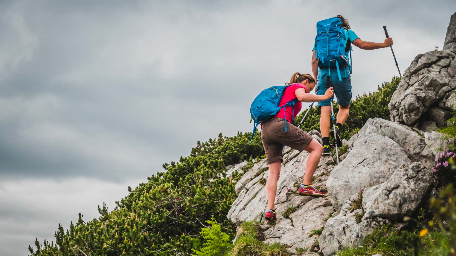 Zwei Bergwanderer steigen über helle Kalksteinplatten und üben Trittsicherheit auf felsigem Gelände in den Berchtesgadener Alpen.