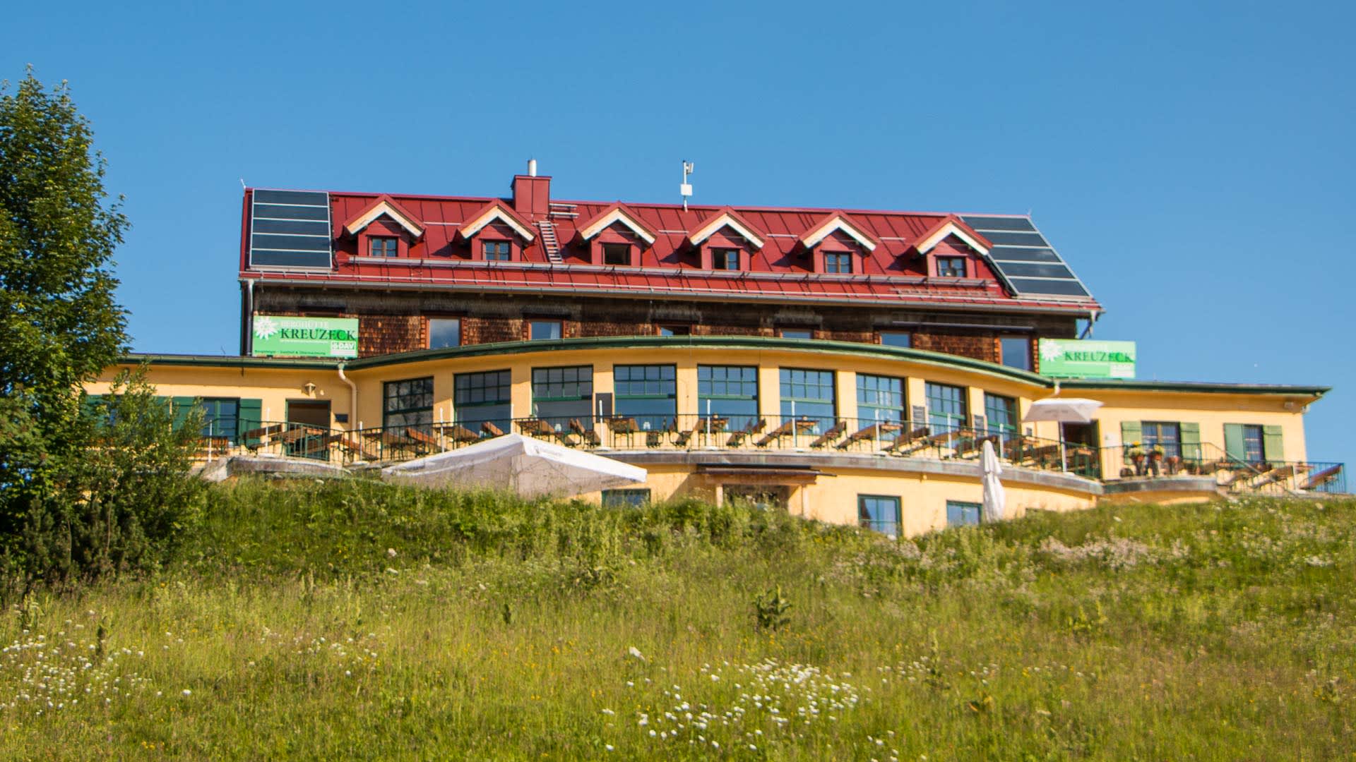 Das Kreuzeckhaus in Garmisch mit Terrasse und Sonnenschirmen, Stützpunkt für Bergwanderungen zur Zugspitze.