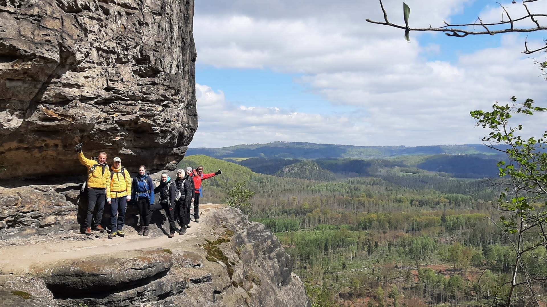Sechs Wanderer bei der Bergwanderung in der Sächsischen Schweiz pausieren auf einem Sandsteinfelsvorsprung