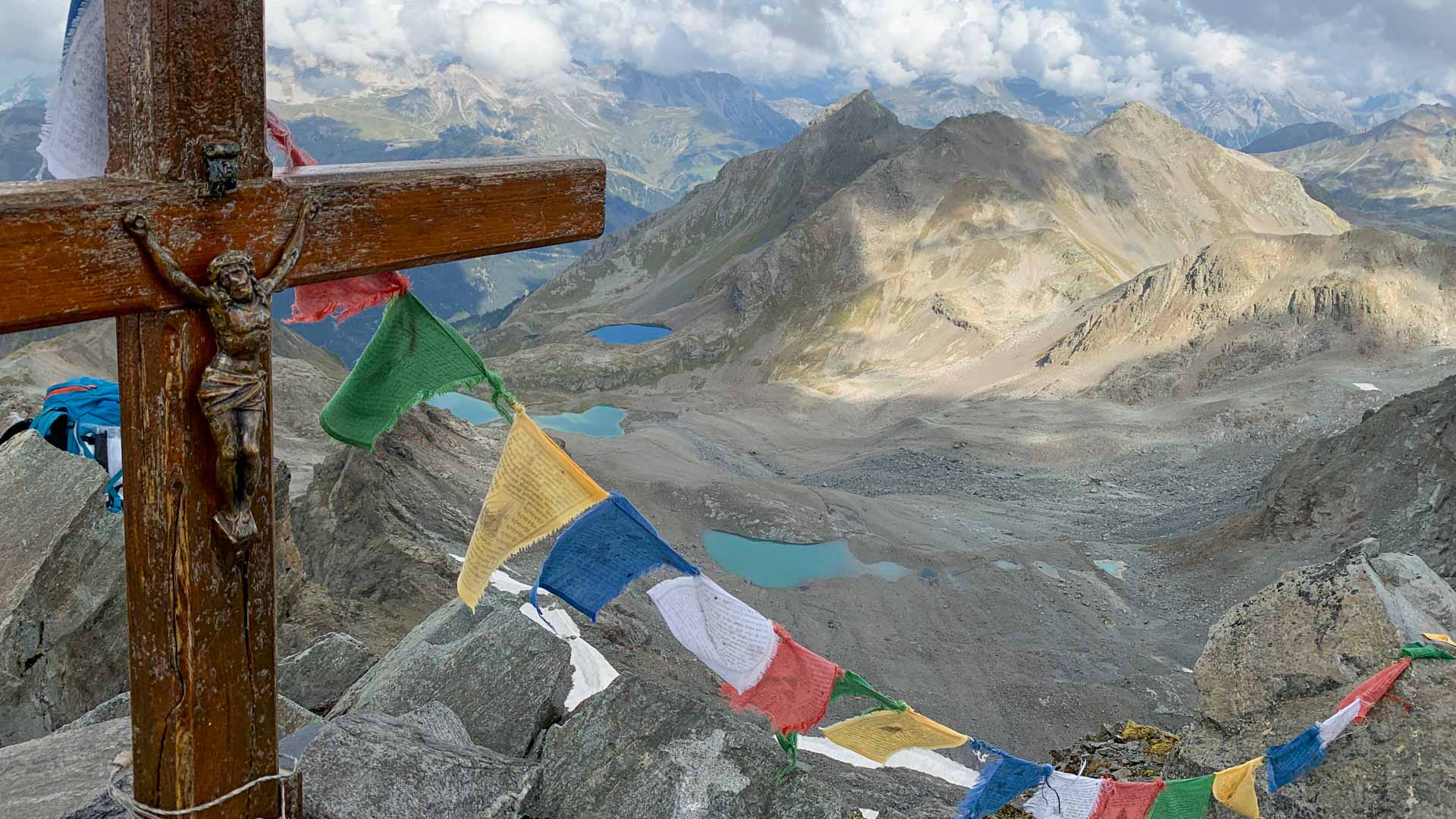 Bergwanderung auf den Scheibler in der Verwallgruppe: hölzernes Gipfelkreuz mit bunten Gebetsfahnen, türkisblaue Bergseen