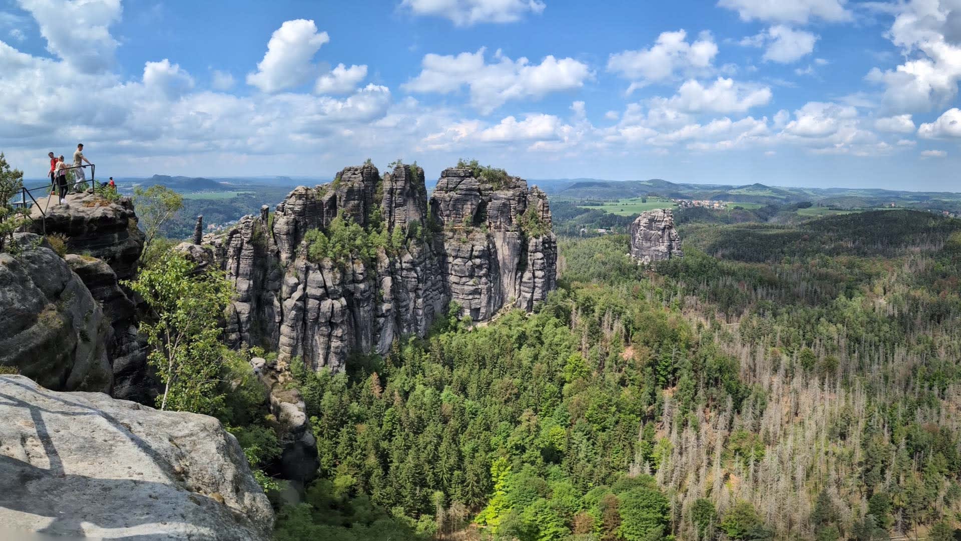 Bergwanderung an den Schrammsteinen in der Sächsischen Schweiz: Vier Wanderer stehen am Metallgeländer eines Felsplateaus