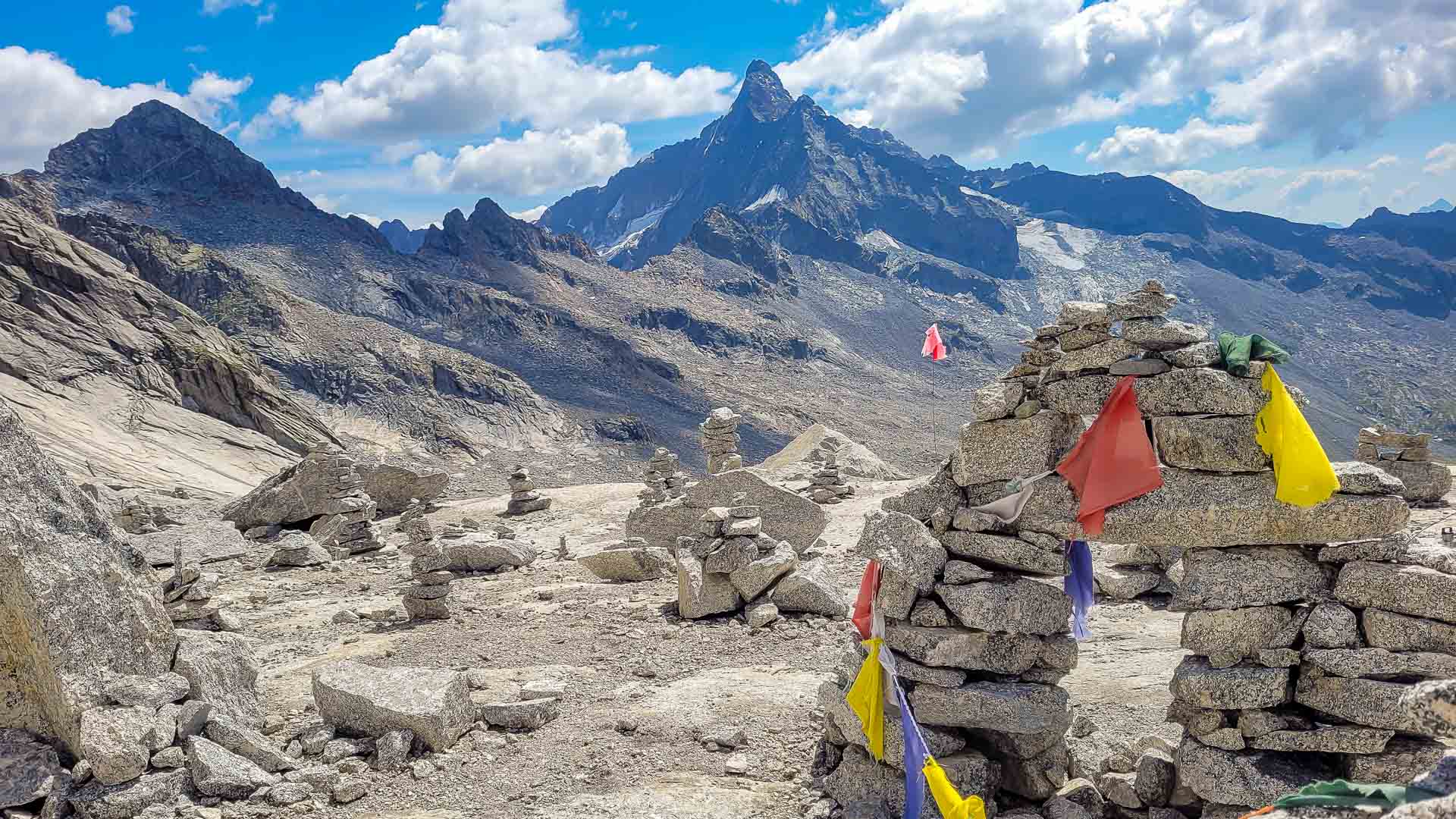 Bergwanderung auf dem Sentiero Roma im Bergell: Cairns mit bunten Wimpeln auf hochalpinem Granitplateau