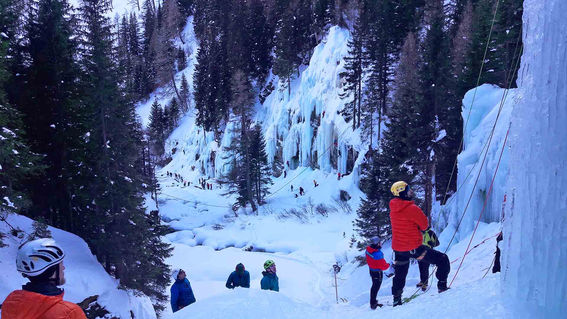 Eiskletterer sichern und klettern an einer blau-weißen Eiswand im Eiskletterpark Osttirol im Winter.