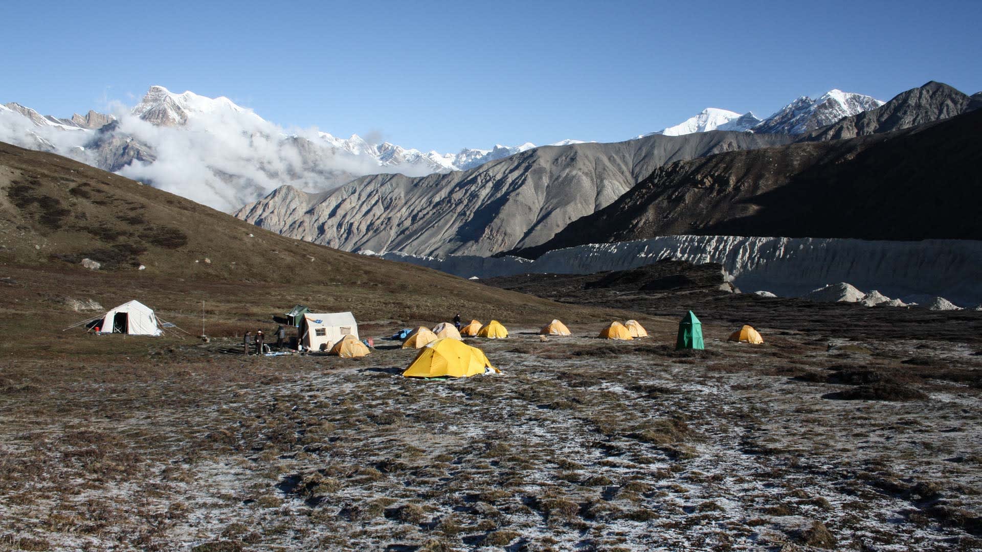 Expedition Himlung Himal: Basislager mit Kuppelzelten vor dem Pangrigletscher, drei Höhenbergsteiger stehen zwischen den Zelten.
