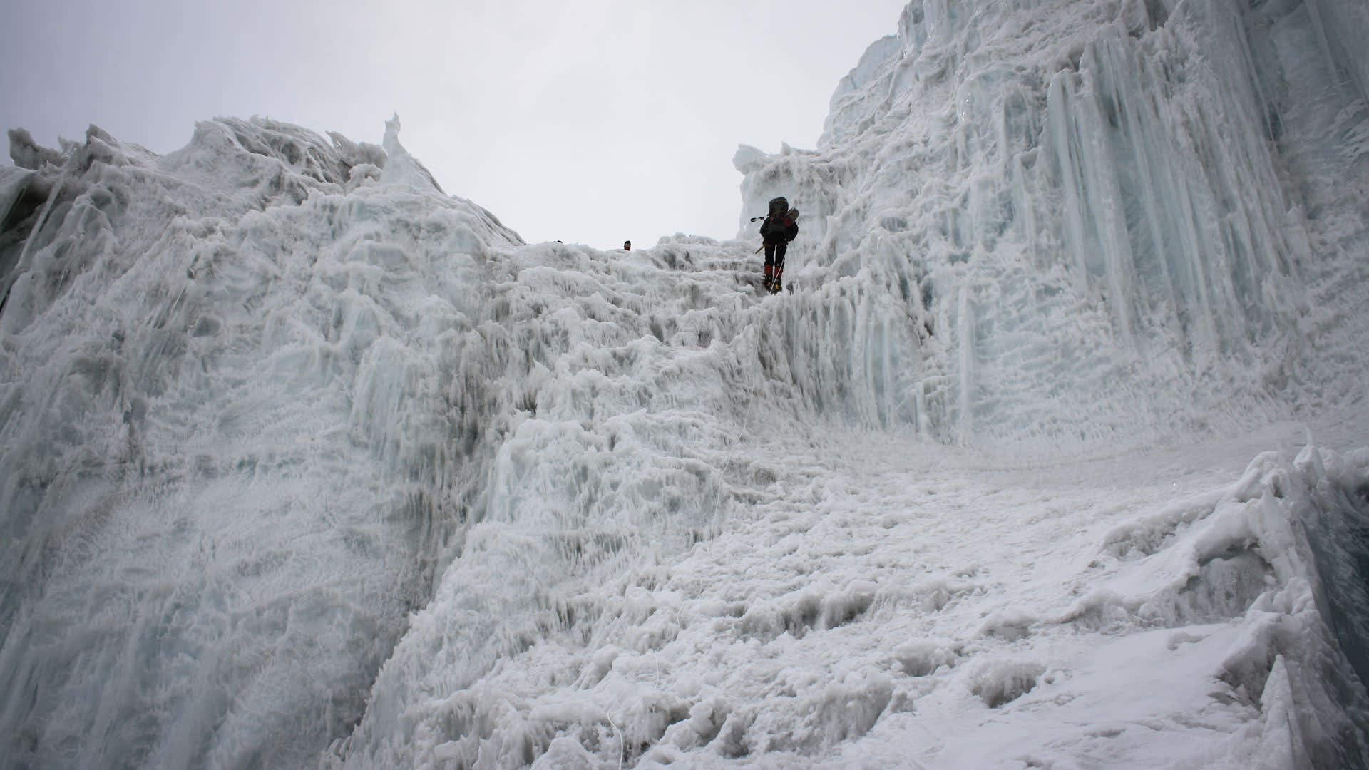 Zwei Höhenbergsteiger seilen an einer steilen Eiswand kurz vor Lager II am Himlung ab, mit Eisäxten und Steigeisen.
