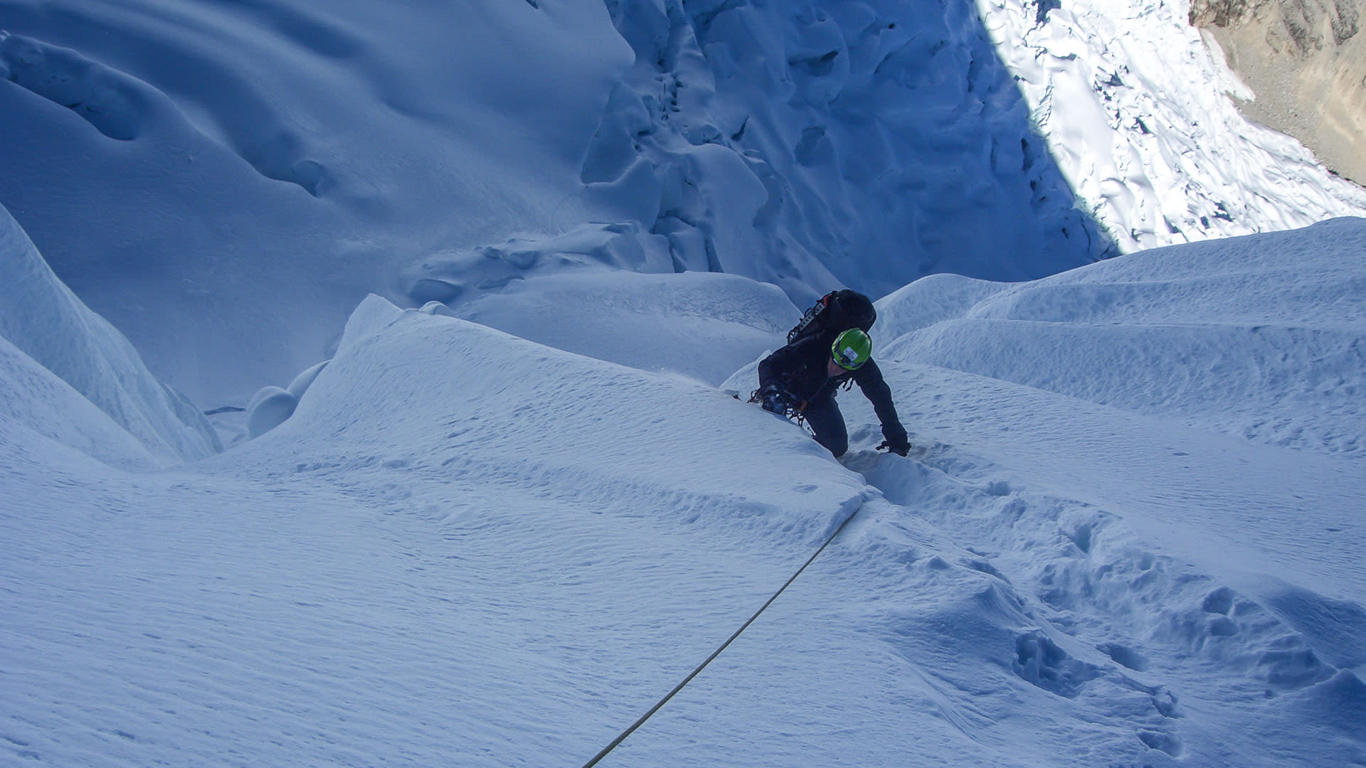 Höhenbergsteiger klettert mit Steigeisen und Seil durch steilen Schneecouloir am Alpamayo in Peru.