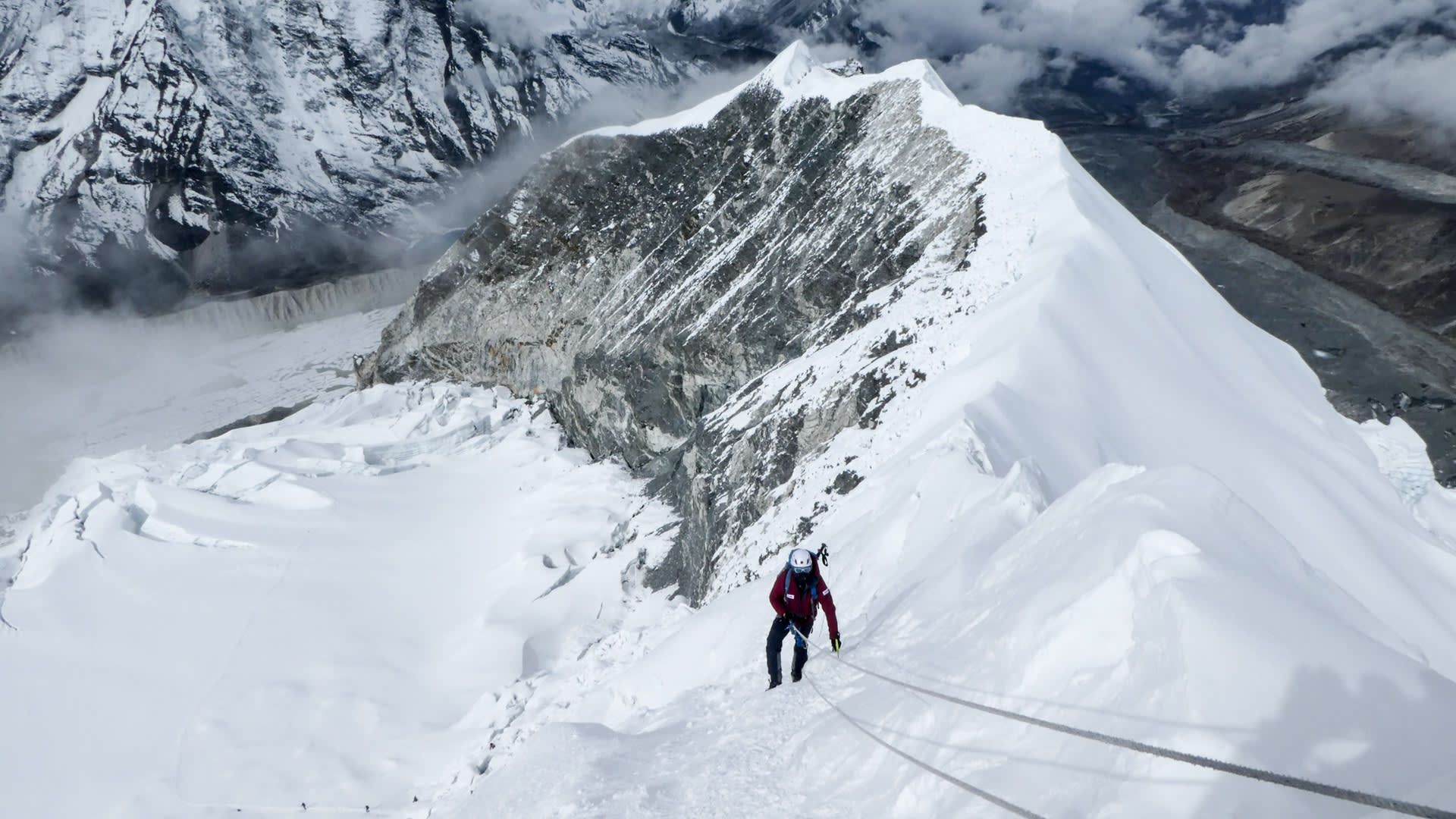 Expedition Island Peak Nepal: Bergsteiger mit Pickel und Seil steigt gesichert einen steilen Schneegrat