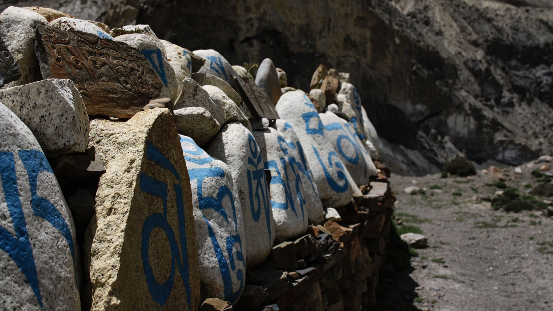Mani-Mauer mit tibetischen Mantra-Inschriften auf blauen Steinen entlang eines Weges im Naar Phu Tal – Expedition Himlung Himal