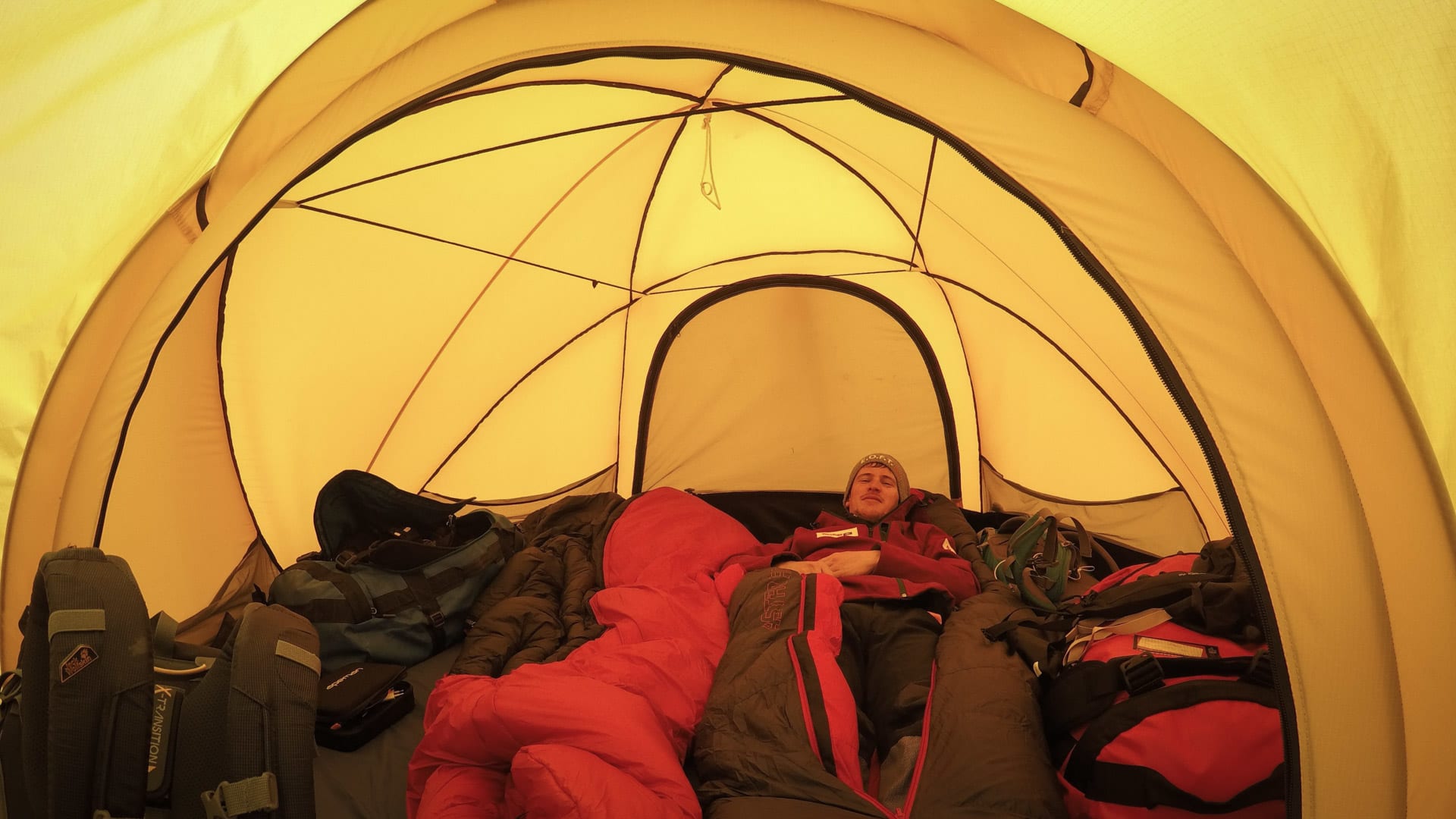 Höhenbergsteiger ruht im Kuppelzelt beim Island Peak Basislager zwischen Rucksäcken und Ausrüstung.