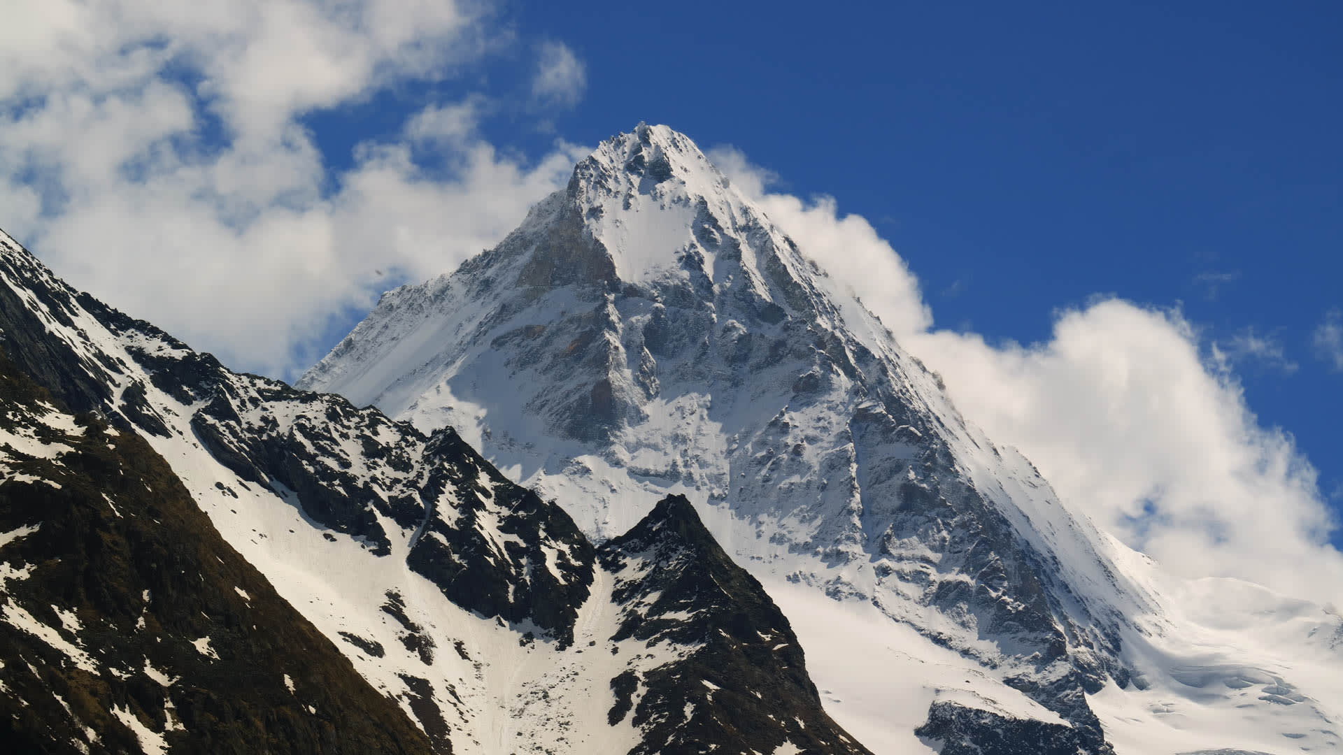 Hochtour auf die Dent Blanche: Schneebedeckter Spitzgipfel mit steilen Flanken und Couloirs unter blauem Himmel im Wallis.