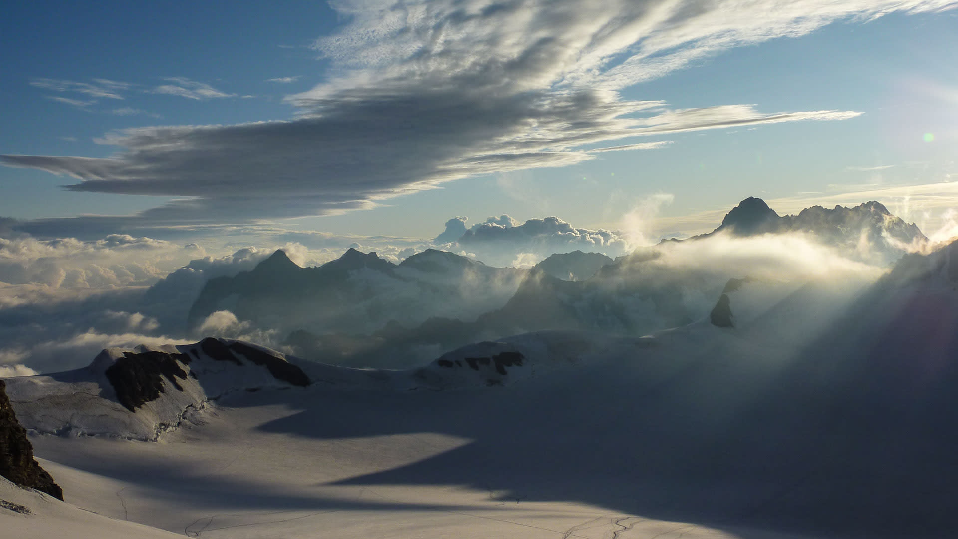 Hochtour am Jungfraugletscher: schneebedecktes Gletscherfeld mit Spuren und Bergkette im Gegenlicht.