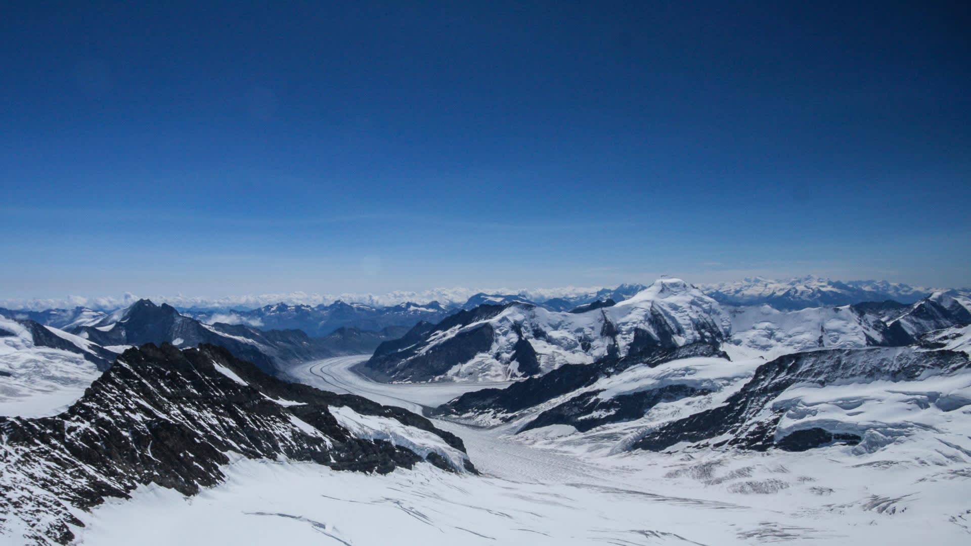 Hochtour vom Jungfraujoch: Vogelperspektive auf einen langen Gletscherstreifen, zerklüftetes Eis und verschneite Gipfelkette