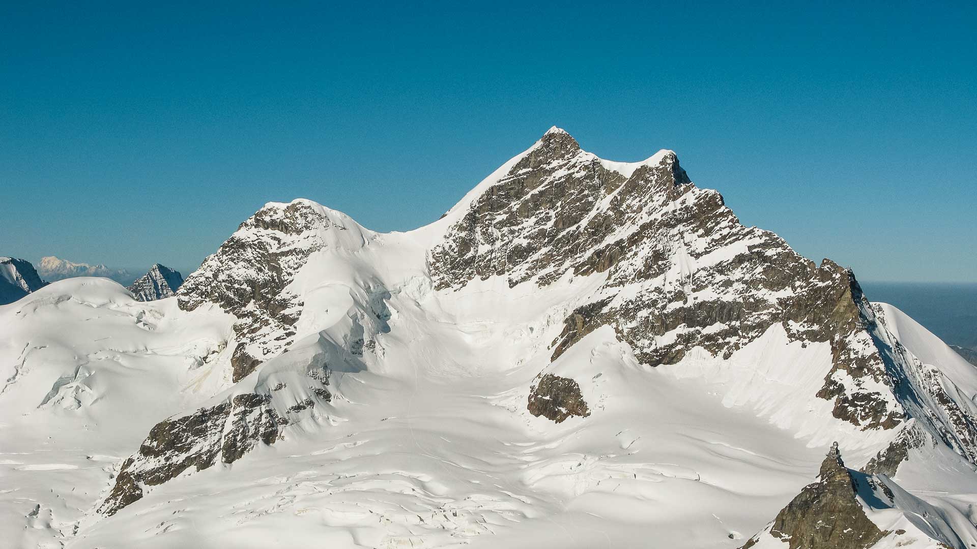 Hochtour am Jungfraujoch: Panoramablick auf zwei schneebedeckte Gipfel mit verbindendem Felsgrat